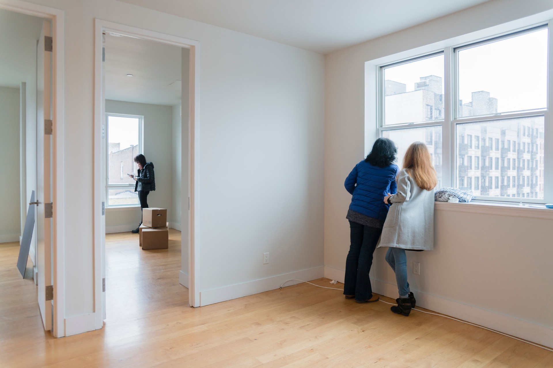 The mature attractive woman, the single mother, and her daughters looking around the new empty apartment.